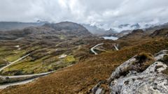 winding mountain road below clouds